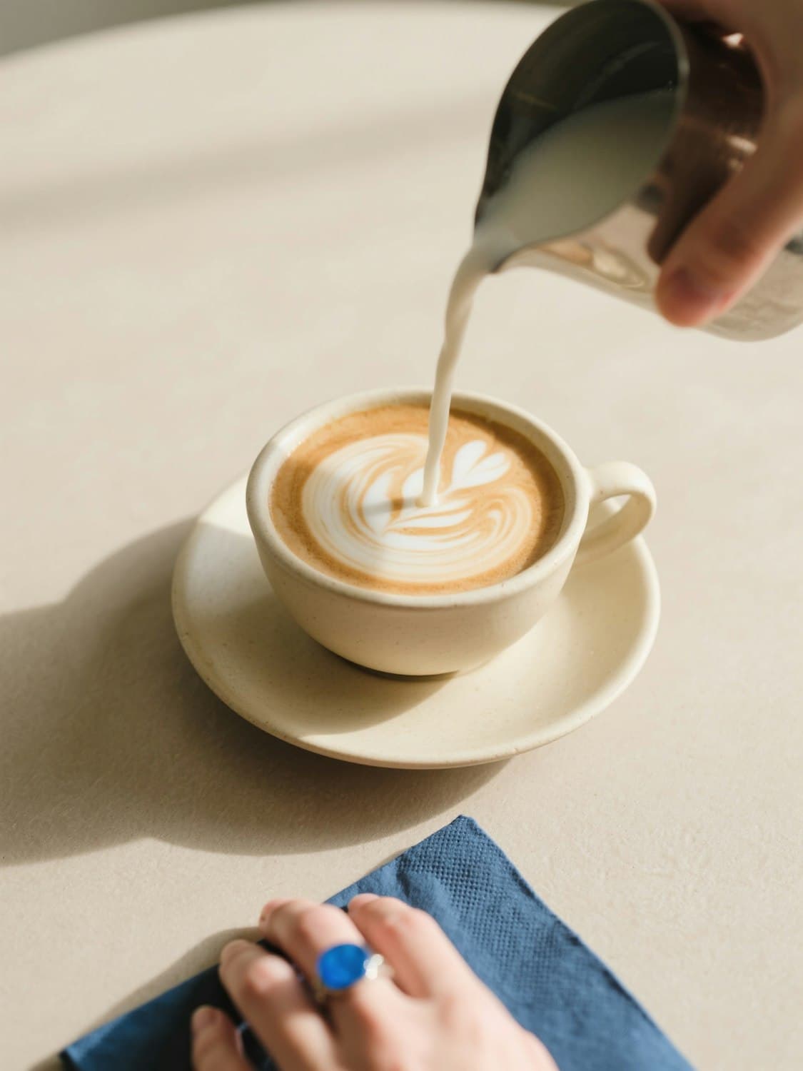 Barista pouring latte art into a ceramic cup